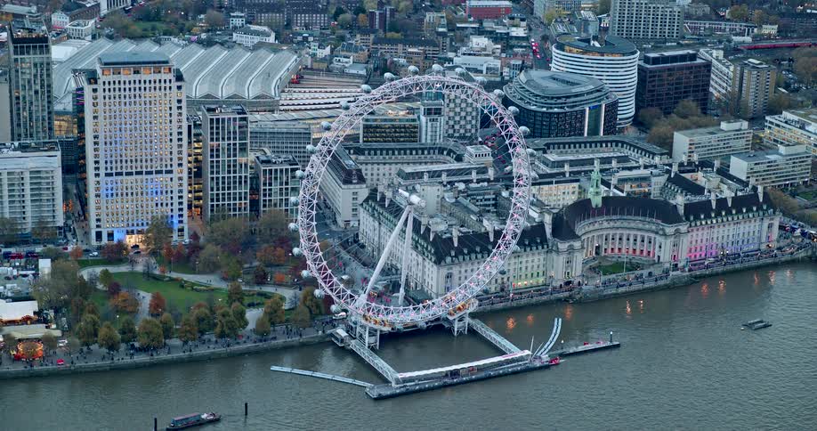 London eye ferris wheel illuminated on the banks of the river thames amid londons urban landscape