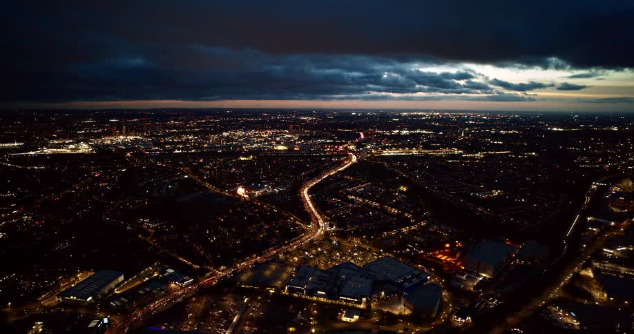 An aerial wide shot captures a major city at night under a dark heavy cloud cover
