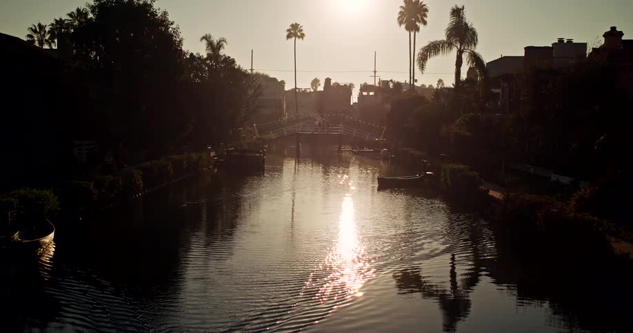 Canal surrounded by palm trees reflecting the setting sun on the water
