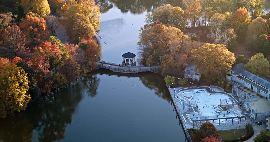 Lake surrounded by autumncolored trees and a small pier with a gazebo