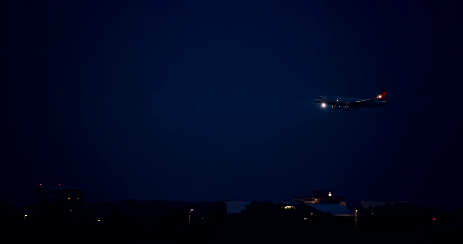 Lights on the jet airplane flash in the darkness as it comes in for a landing
