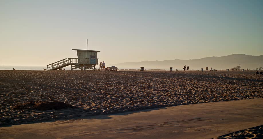 A small observation structure on the sand of a beach with some people around it