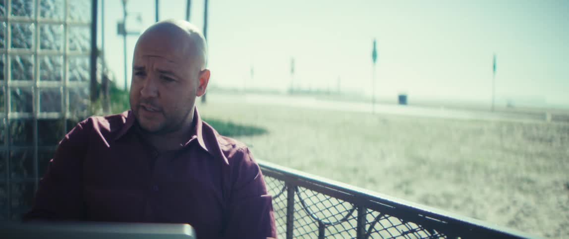 A man gestures while having a conversation via his laptop