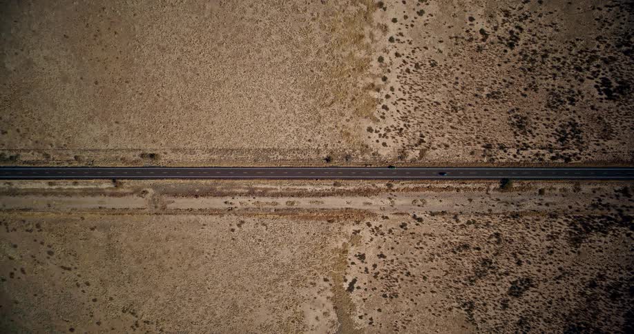 An aerial view of a huge asphalt highway that runs through a desert region