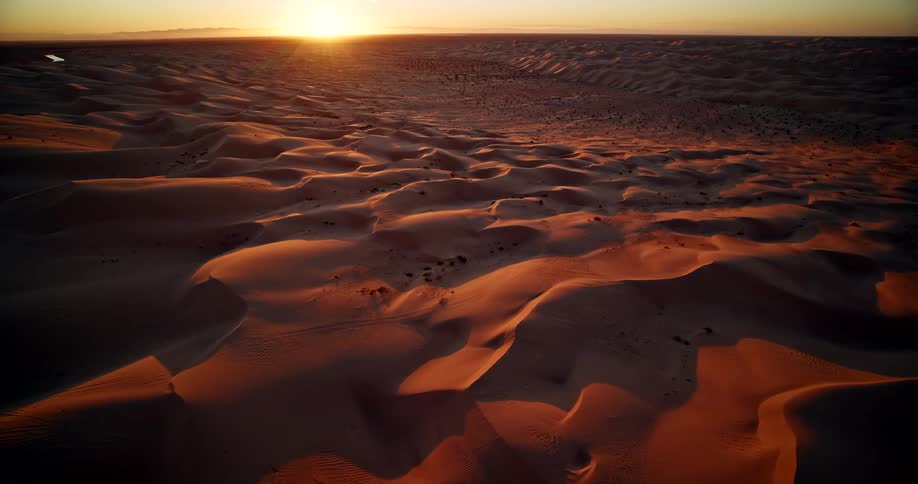 Aerial of sand dunes in a vast desert at sunset