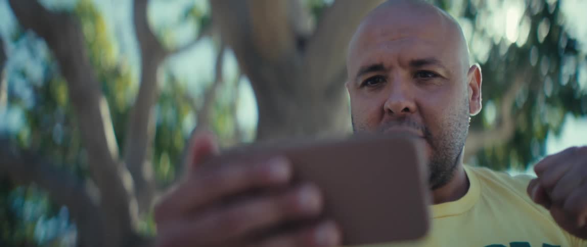 Man looking at his phone with a surprised expression and clenched fist