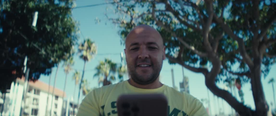 A man is walking outside looking at a tablet
