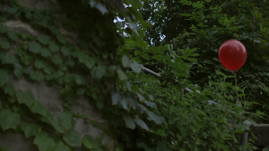Red balloon floats through the trees