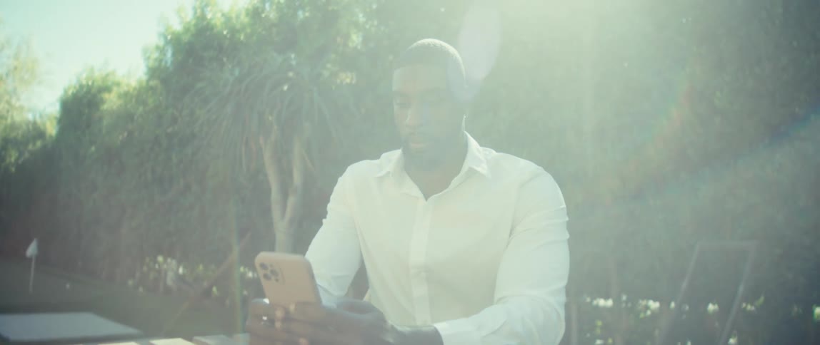 Man sitting outside at a table texting on his phone