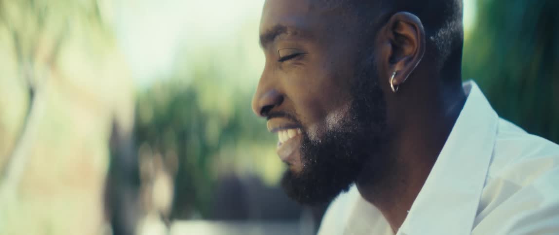 Man smiling outdoors under natural light