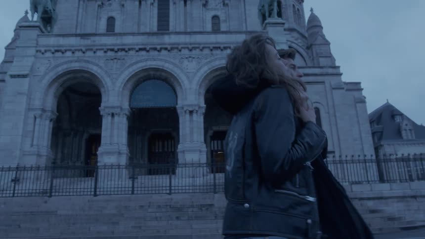 The couple walk past the large stone building