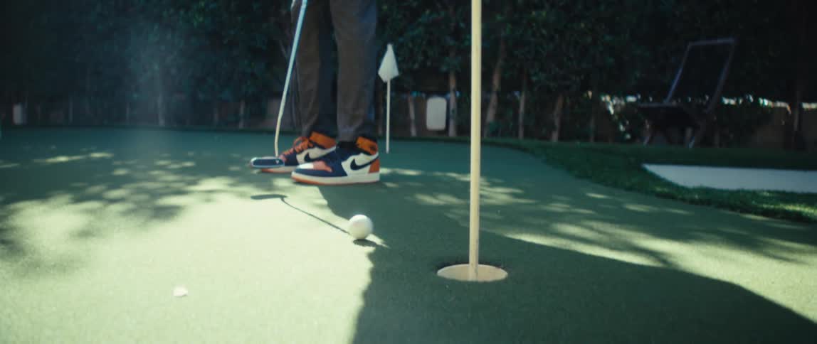 A man plays golf putting the ball into the hole on the course on a sunny day
