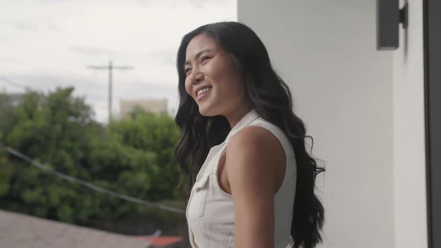 Close up portrait of a young asian woman standing at a balcony during daytime