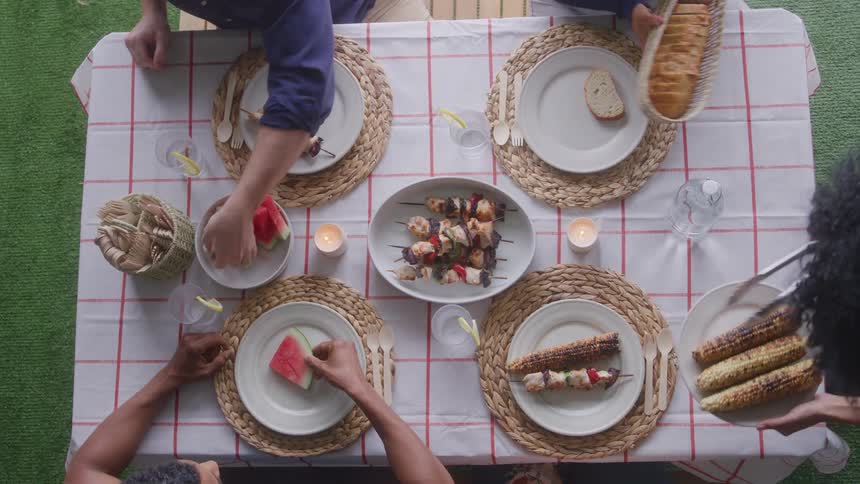 Several people all serve themselves food while seated at a table