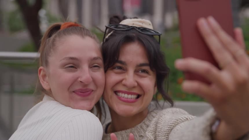 Friends smile while taking a selfie outdoors