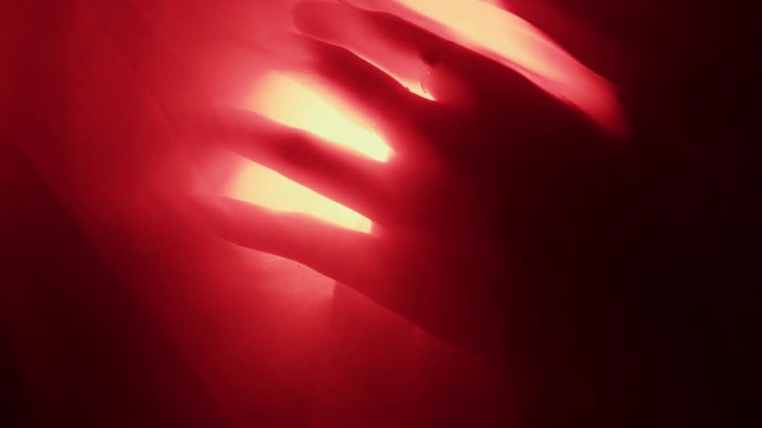 A hand over an object emitting a pulsating red light