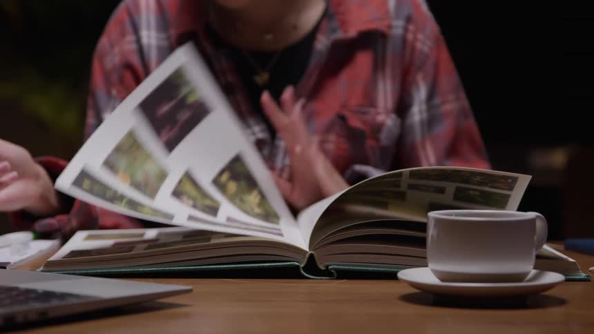The woman is looking at photos in a book