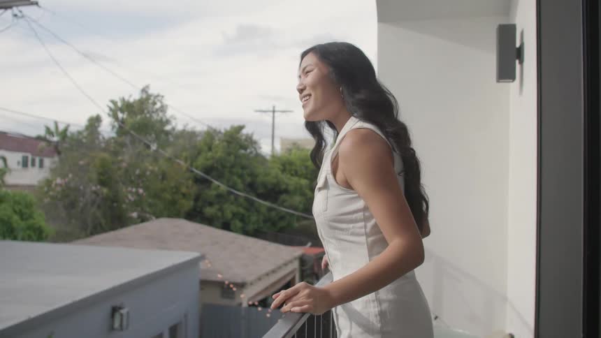 Woman enjoys the fresh air while standing on her balcony