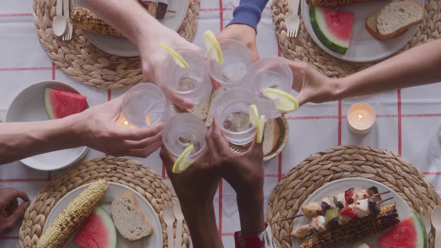 The arms of several people clinking glasses of water with lemon slices in them
