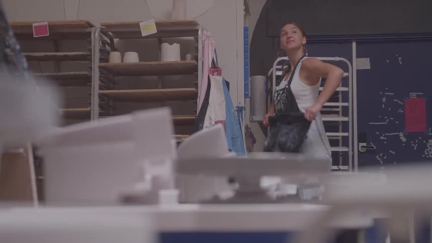 Woman putting on an apron in a pottery studio