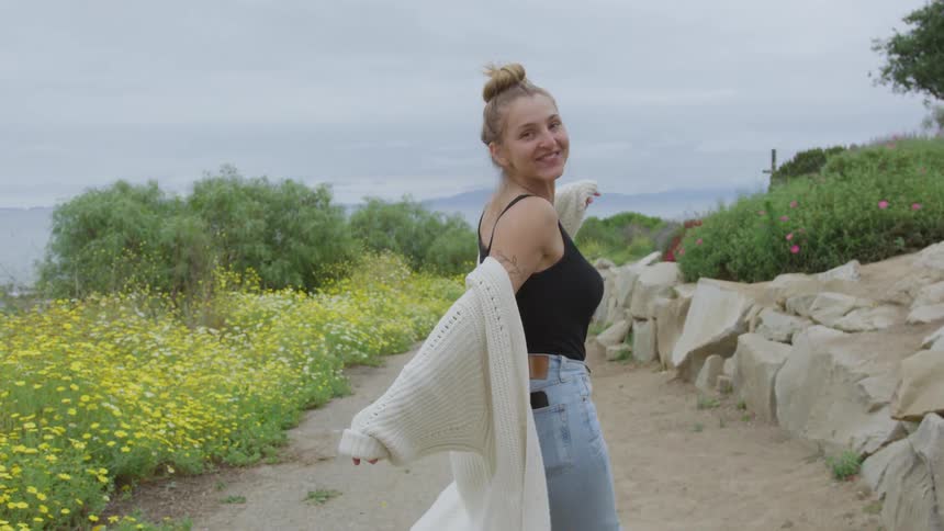 Woman smiling while walking along a flowerlined trail