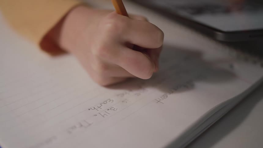 A person is using a pencil to write in a notebook