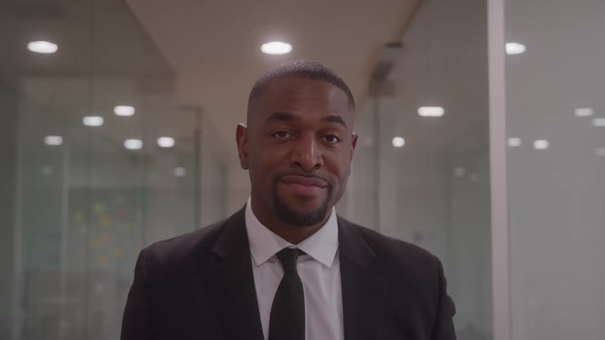 Man in a suit and tie looking forward in an office hallway