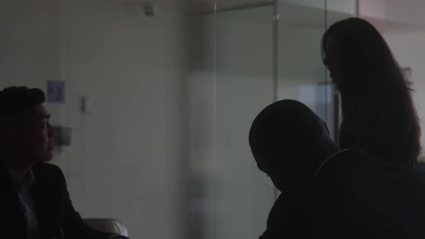 The woman walks as she talks with two men at a meeting