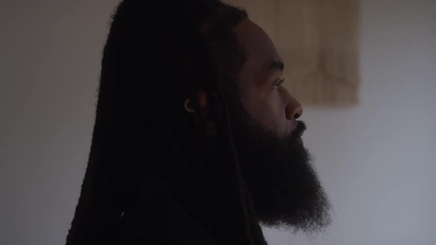 The profile of a black man with dreadlocks and a beard he appears to be looking forward and thinking