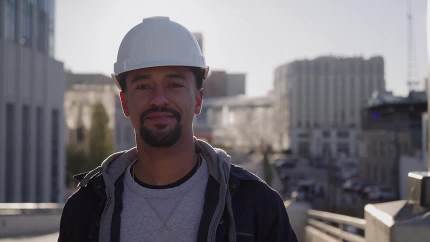 The construction worker is standing on the bridge