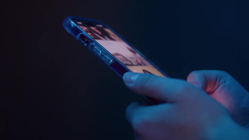 A persons hands are shown holding a smartphone and scrolling