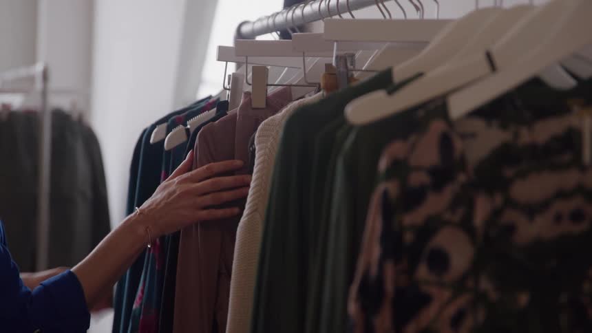 Woman looking through clothes hanging on a rack in a store