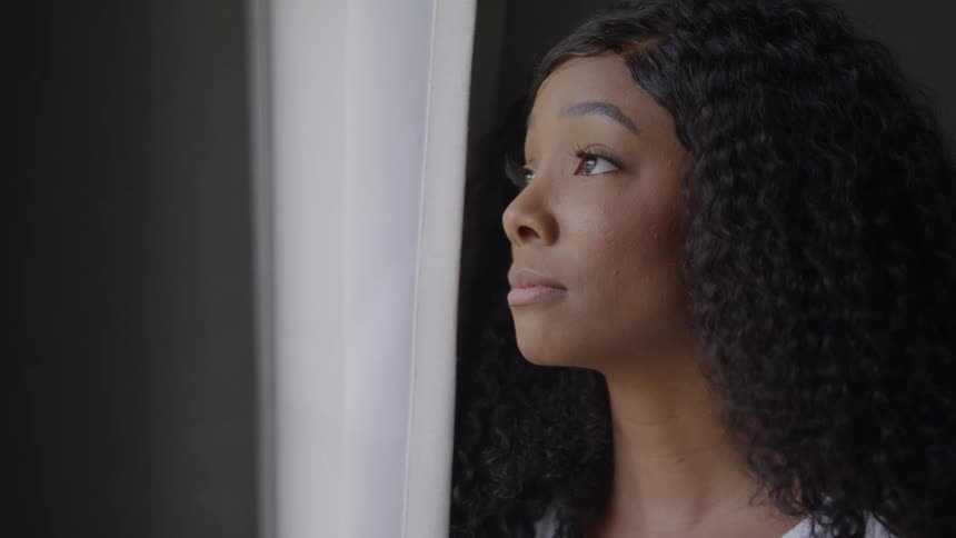 A woman looks sad as she looks out of a window
