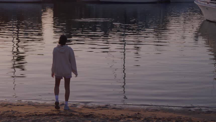 A young woman finishes a job stopping by a body of water reflecting boats