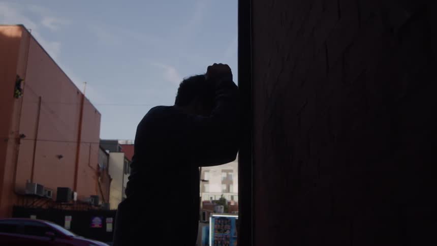 Man leaning against the wall showing emotional exhaustion
