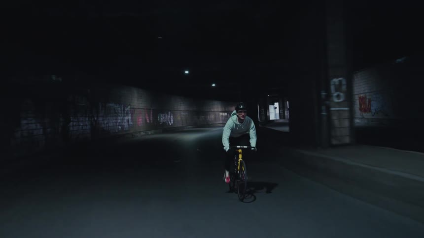 Man rides his bicycle fast on a road through an overpass