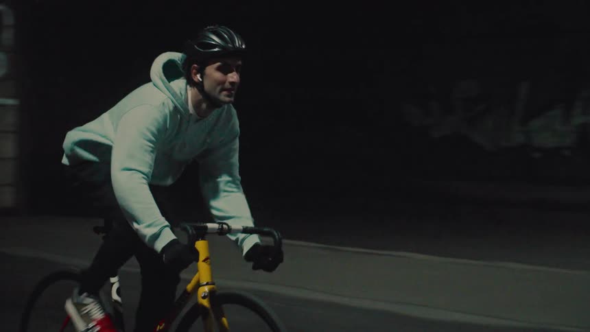 A young man cycling under a tunnel while wearing a helmet at midday