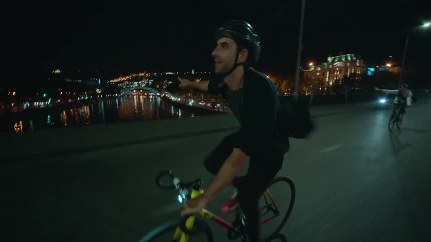The man gives a turning signal with his arm while riding a bike