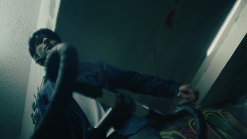 Man wearing a helmet holds a yellow bicycle in a dim indoor setting