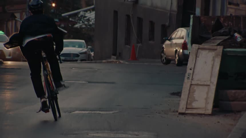 Cyclist turns on a busy street between parked cars and moving vehicles