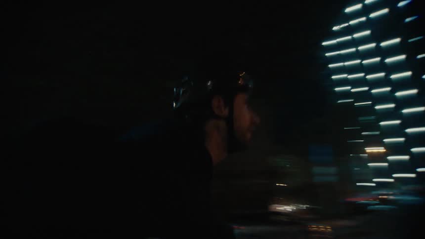 Cyclist turns on a brightly lit avenue at night