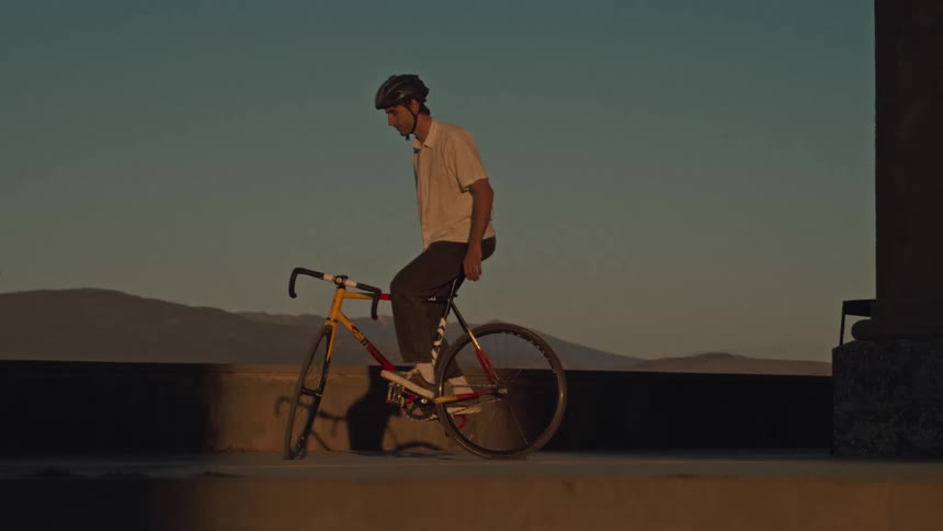 Male cyclist balances on his bicycle as fog covers the hills in the background