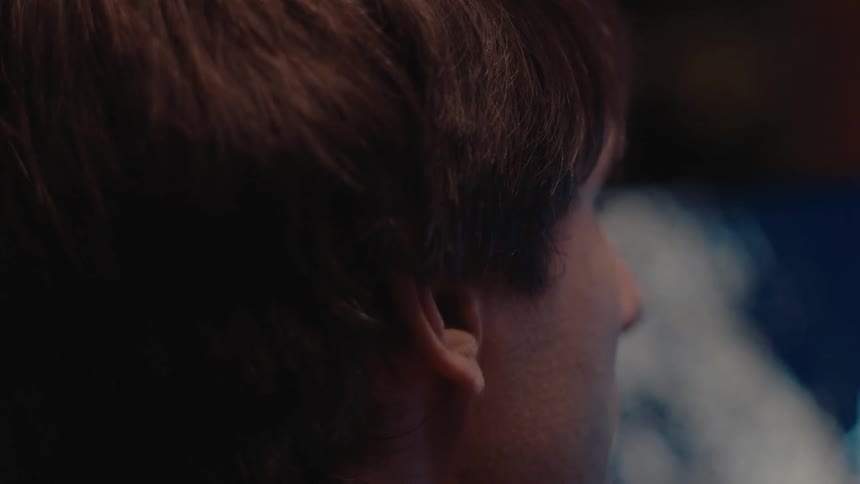 Man intently watches a bright screen in front of him