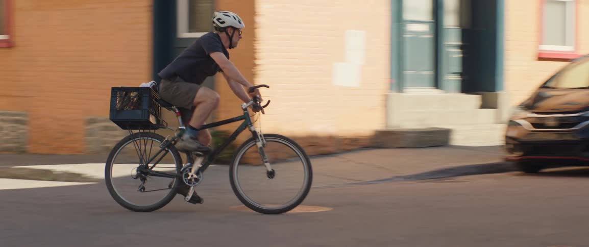 Male cyclist pedals through an intersection in a residential neighborhood