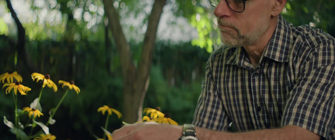 Florist sitting outside inspecting yellow flowers