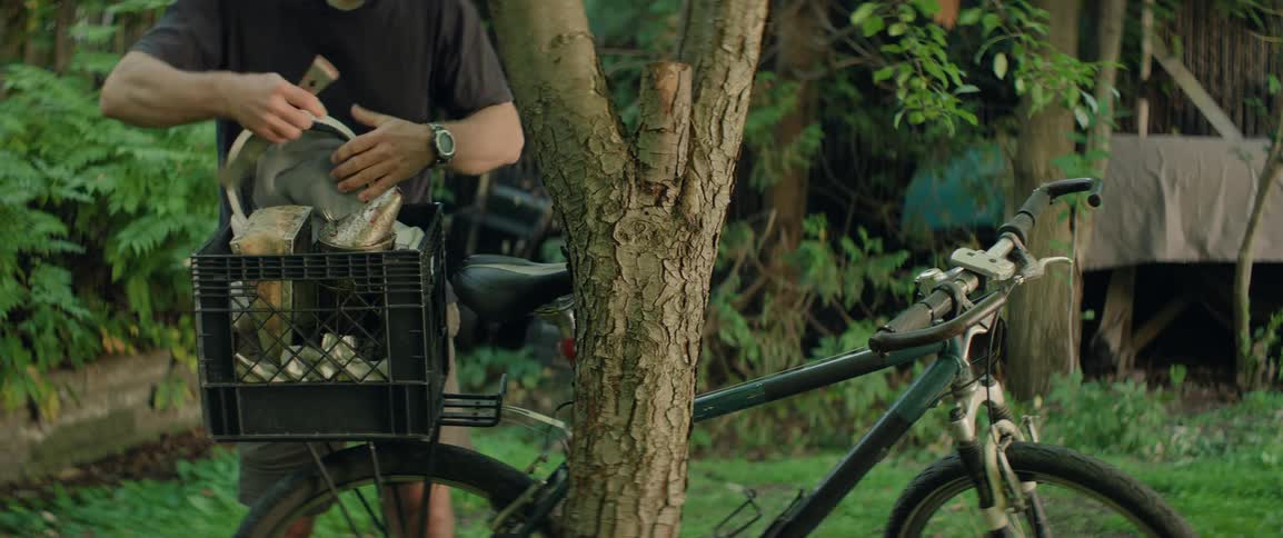 Man stores beekeeping equipment in a box attached to his bicycle and rides away