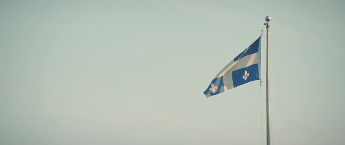 Flag of quebec flutters in the wind under a clear sky