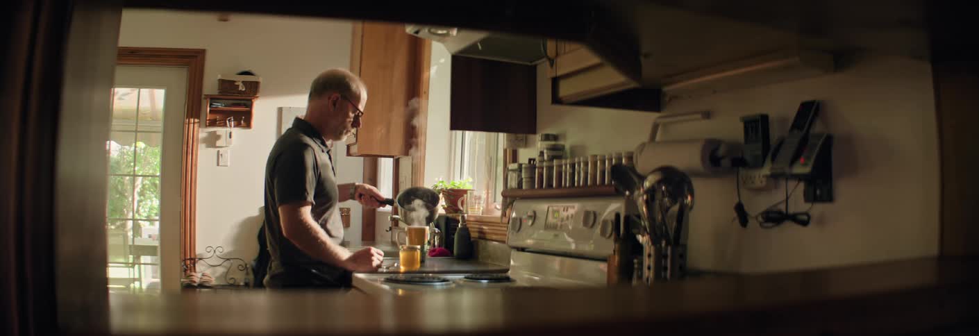 Man prepares a hot drink in a kitchen lit by morning sunlight