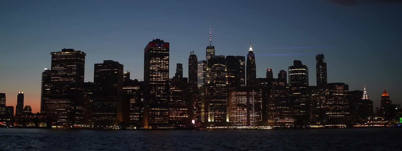 City skyline lit up at nightfall with reflections on the river