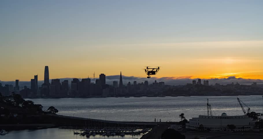 Drone flies along the coast with the metropolitan skyline in the distance